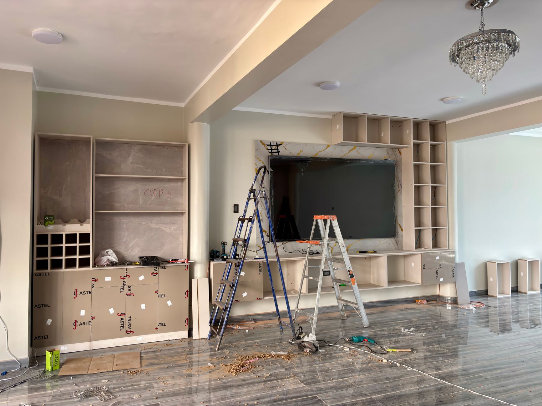 Interior renovation in progress with built in shelving, ladders, and tools in a living room
